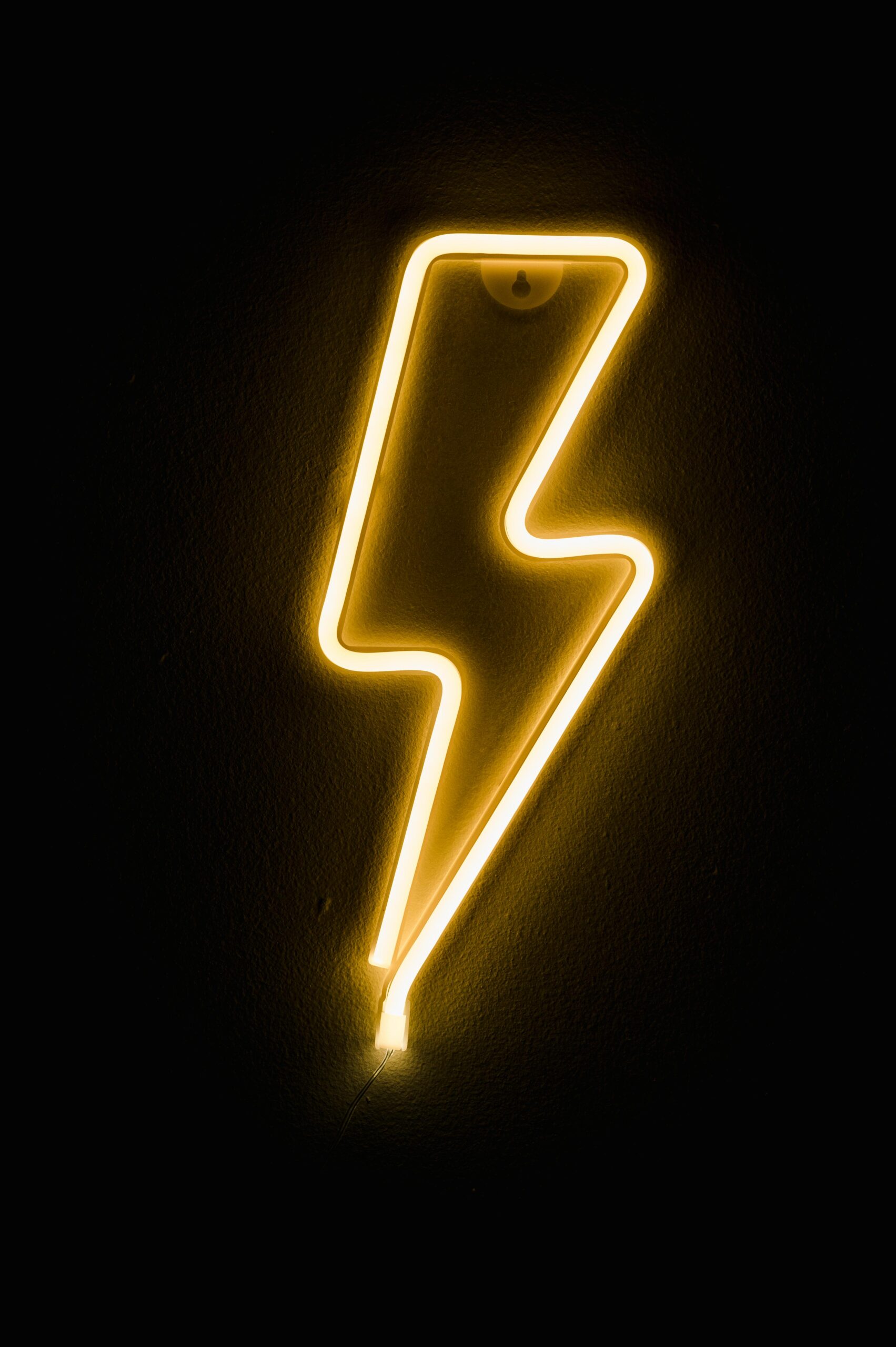 Illuminated neon lightning bolt sign glowing on a dark background.